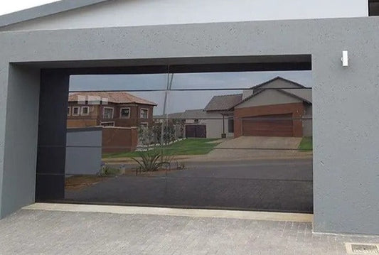 Modern frameless garage door with sleek, reflective finish, installed in a contemporary home exterior. Enhance curb appeal and style with this durable, non-insulated garage door designed for modern architecture. Perfect for homeowners seeking a sophisticated, minimalist look.